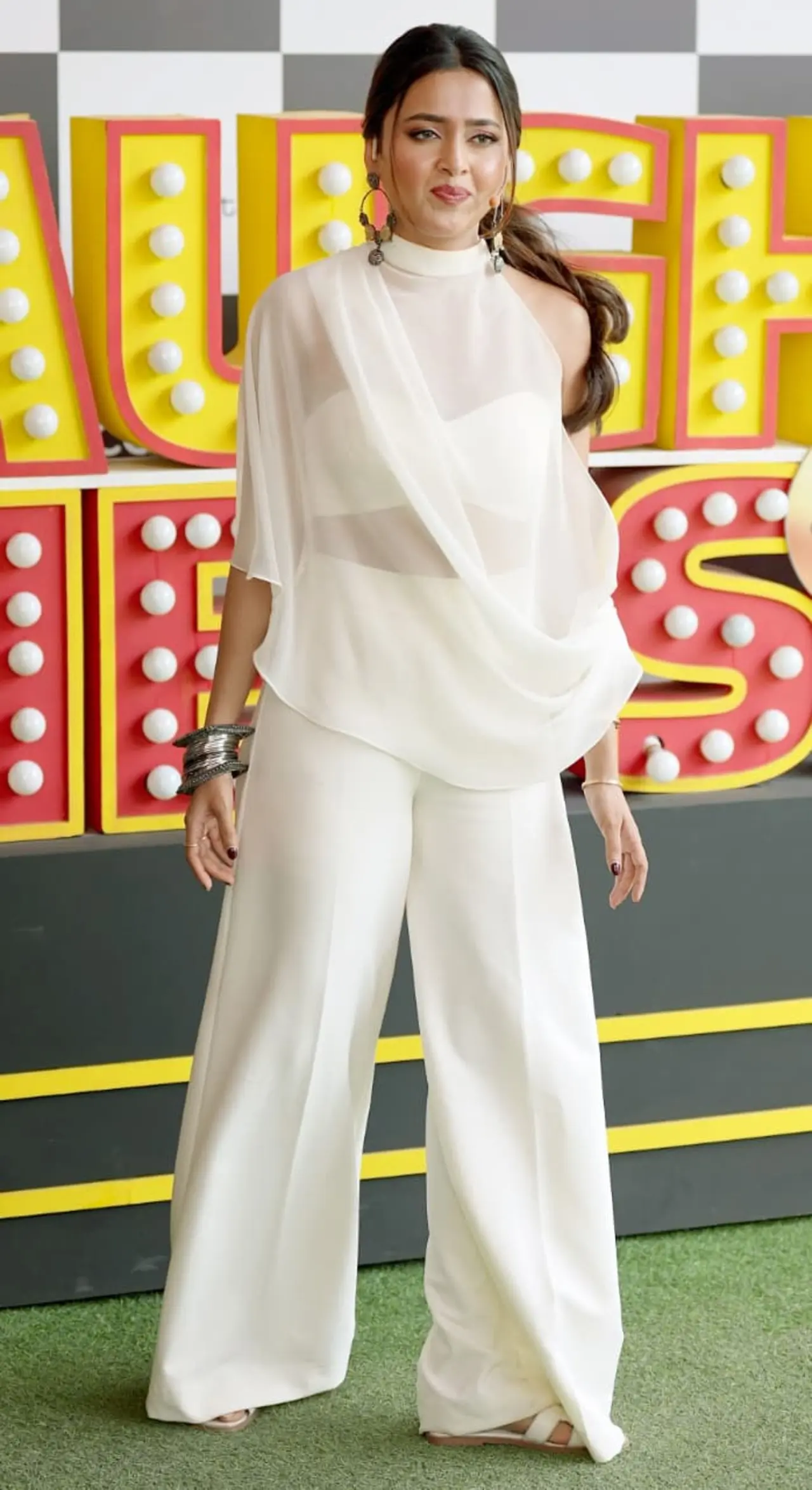 <p><span class="hover:entity-accent entity-underline inline cursor-pointer align-baseline"><span class="whitespace-normal">Tejasswi Prakash</span></span> was spotted shooting for Laughter Chefs, looking effortlessly graceful in an all-white ensemble. She wore a flowy draped top paired with wide-leg trousers, accessorised with statement earrings and bangles.</p>